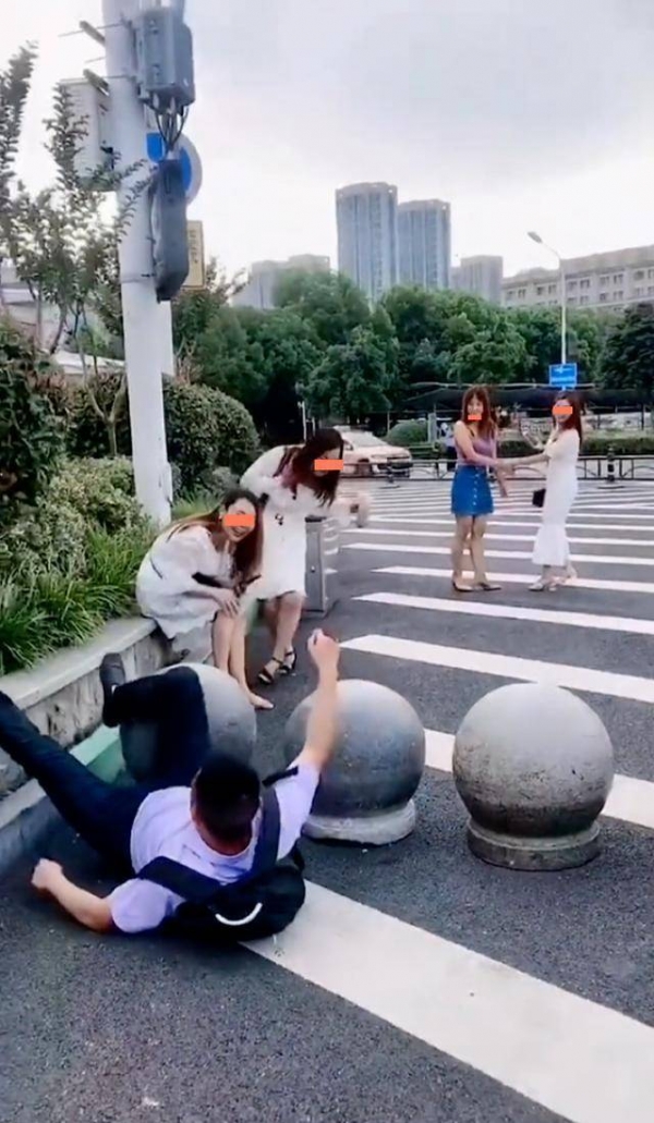 男子走路只顾着看美女撞到石墩并摔倒遭坐在路边的女子嘲笑