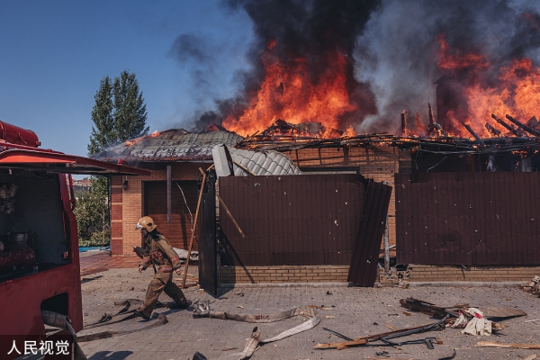 当地时间2022年7月27日，顿涅茨克地区巴赫穆特，消防队员在一所遭遇炮击的房屋旁灭火。人民视觉 图