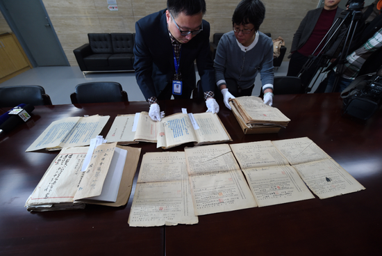  南京市档案馆人员展示相关档案。（2015年记者孙参摄）