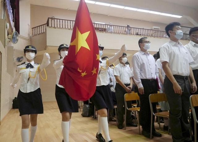  9月1日，在香港教育工作者联会黄楚标中学，白衣蓝帽护旗升旗小队正步走向旗杆。新华社记者 王申 摄