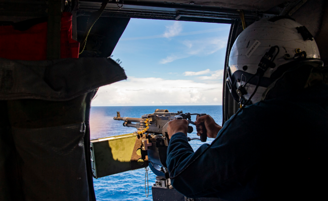 “塔尔萨”号濒海战斗舰舰载直升机机组人员使用舱门机枪射击
