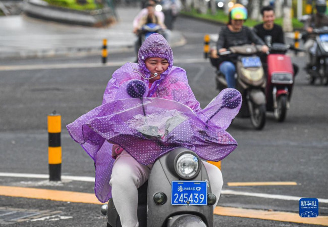 10月13日，市民迎风骑行在海口街头。