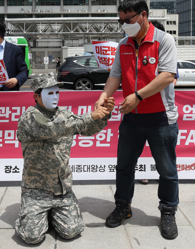 6月16日，美大使馆前，韩国民众假扮美军，跪地戴手铐。